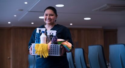 PCT Janitorial - smiling cleaner with supplies in office setting