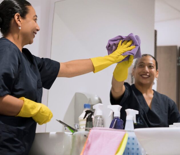 PCT Janitorial staff cleaning mirror in commercial bathroom PCT Janitorial staff cleaning mirror in commercial bathroom