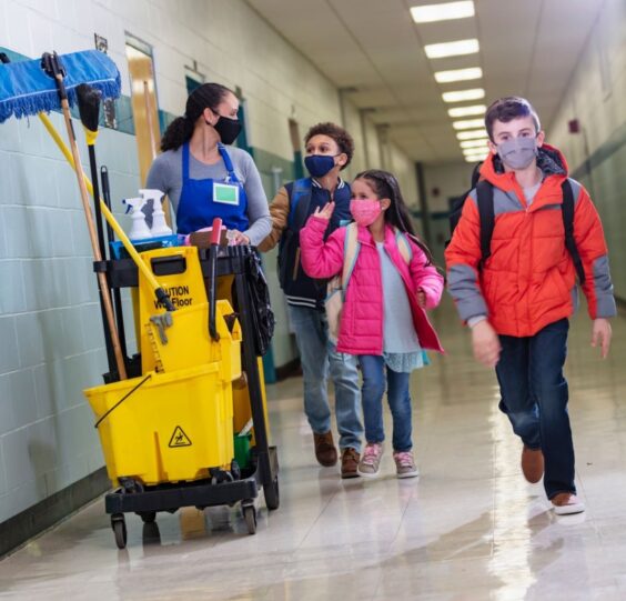 Students and Cleaner Walking in the Corridor